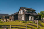 Experience rustic charm and modern comfort in this beautifully renovated farmhouse, featuring dark wood siding and a sleek metal roof.