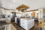 Experience rustic charm in this spacious kitchen, featuring a stunning wooden pot rack suspended from the ceiling and a large island perfect for meal prep.