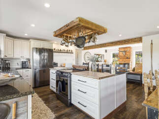 Experience rustic charm in this spacious kitchen, featuring a stunning wooden pot rack suspended from the ceiling and a large island perfect for meal prep.