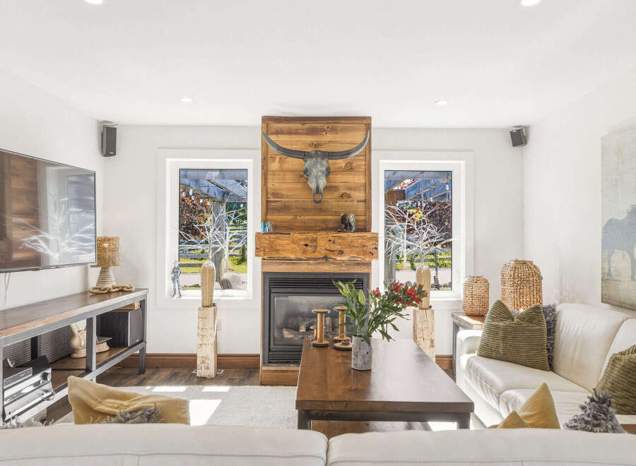 Experience rustic charm in this inviting living room, featuring a striking wooden fireplace adorned with a longhorn skull.