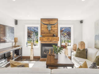 Experience rustic charm in this inviting living room, featuring a striking wooden fireplace adorned with a longhorn skull.