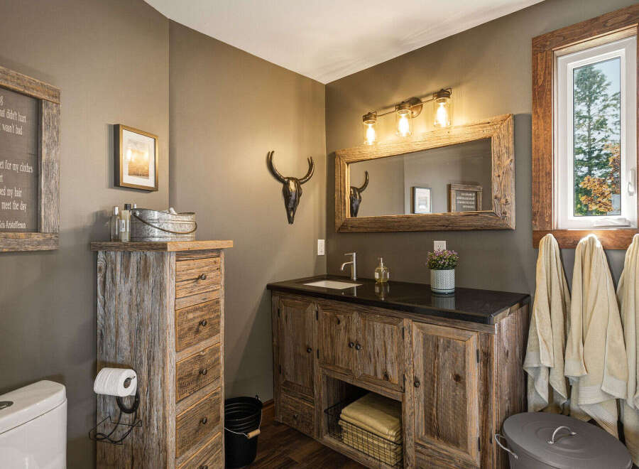 This rustic bathroom features a charming wooden vanity with ample storage and a granite countertop.