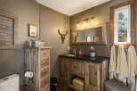 This rustic bathroom features a charming wooden vanity with ample storage and a granite countertop.