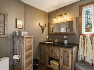 This rustic bathroom features a charming wooden vanity with ample storage and a granite countertop.