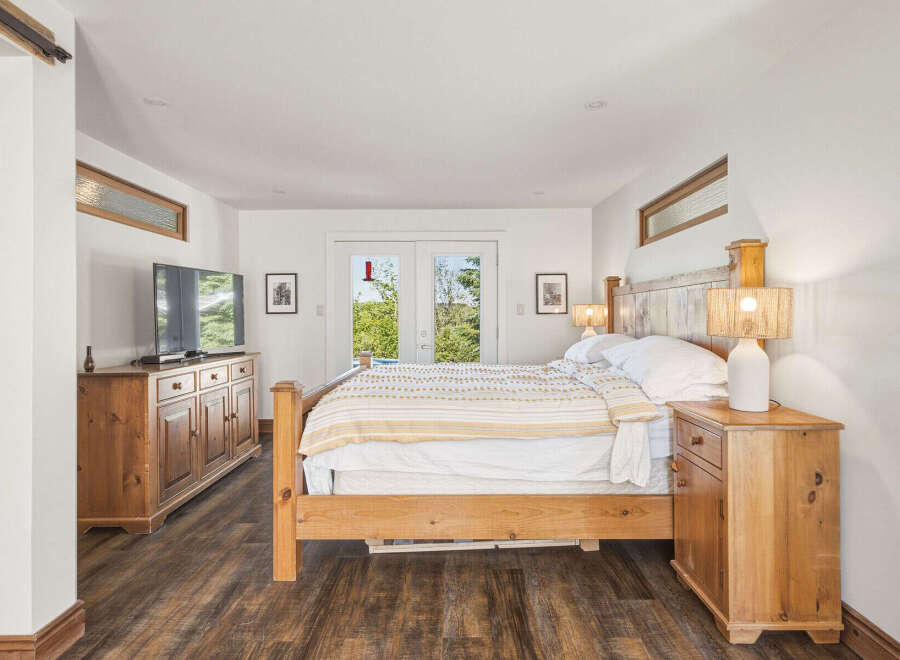 Experience ultimate comfort in this serene bedroom, featuring a spacious wooden bed adorned with a cozy striped comforter.