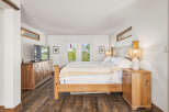 Experience ultimate comfort in this serene bedroom, featuring a spacious wooden bed adorned with a cozy striped comforter.