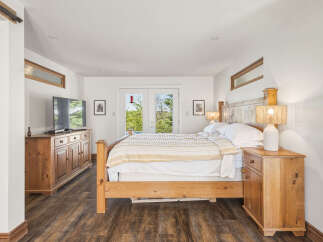 Experience ultimate comfort in this serene bedroom, featuring a spacious wooden bed adorned with a cozy striped comforter.