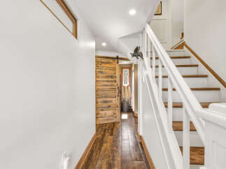 This charming home features a rustic wooden barn door leading to a bright interior.