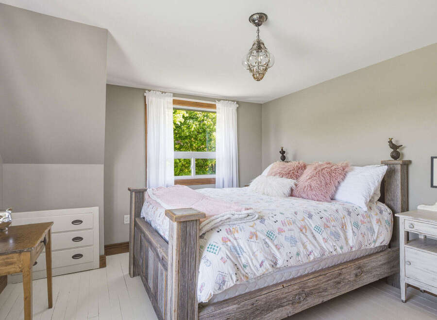 This charming bedroom features a rustic wooden bed adorned with a whimsical duvet cover and plush pink pillows.