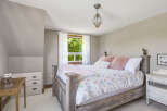 This charming bedroom features a rustic wooden bed adorned with a whimsical duvet cover and plush pink pillows.