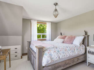 This charming bedroom features a rustic wooden bed adorned with a whimsical duvet cover and plush pink pillows.
