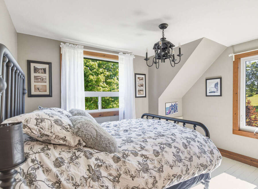 This charming bedroom features a cozy queen-size bed with a decorative floral duvet and plush pillows, perfect for a restful night's sleep.