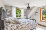 This charming bedroom features a cozy queen-size bed with a decorative floral duvet and plush pillows, perfect for a restful night's sleep.