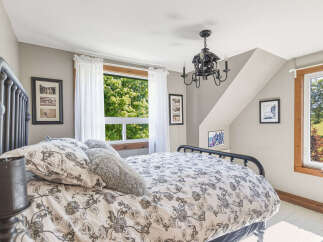 This charming bedroom features a cozy queen-size bed with a decorative floral duvet and plush pillows, perfect for a restful night's sleep.