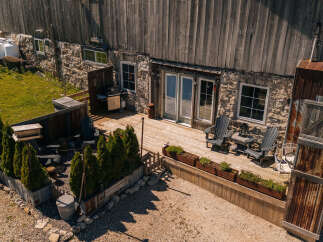 Enjoy outdoor living on this charming wooden deck, complete with comfortable Adirondack chairs and a small table, perfect for morning coffee or evening relaxation.