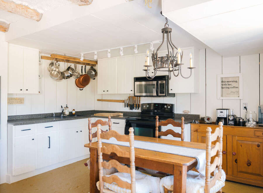 Experience rustic charm in this cozy kitchen, featuring white paneled walls and a charming wooden dining set.
