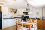 Experience rustic charm in this cozy kitchen, featuring white paneled walls and a charming wooden dining set.