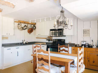Experience rustic charm in this cozy kitchen, featuring white paneled walls and a charming wooden dining set.