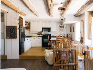 Step into a charming rustic retreat featuring exposed wooden beams and a cozy kitchen area.