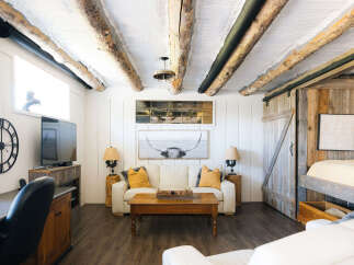 Experience rustic charm and modern comfort in this unique living space, featuring exposed log beams and a cozy farmhouse aesthetic.