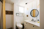 This charming bathroom features a white shiplap design, a rustic wooden coat rack, and a bright yellow gingham shower curtain.