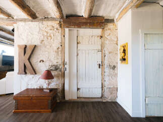 Discover rustic charm in this unique living space, featuring exposed wooden beams and textured stone walls that add character and warmth.