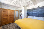 Experience rustic charm in this unique bedroom featuring a striking dark wood paneled headboard and a vibrant yellow duvet.