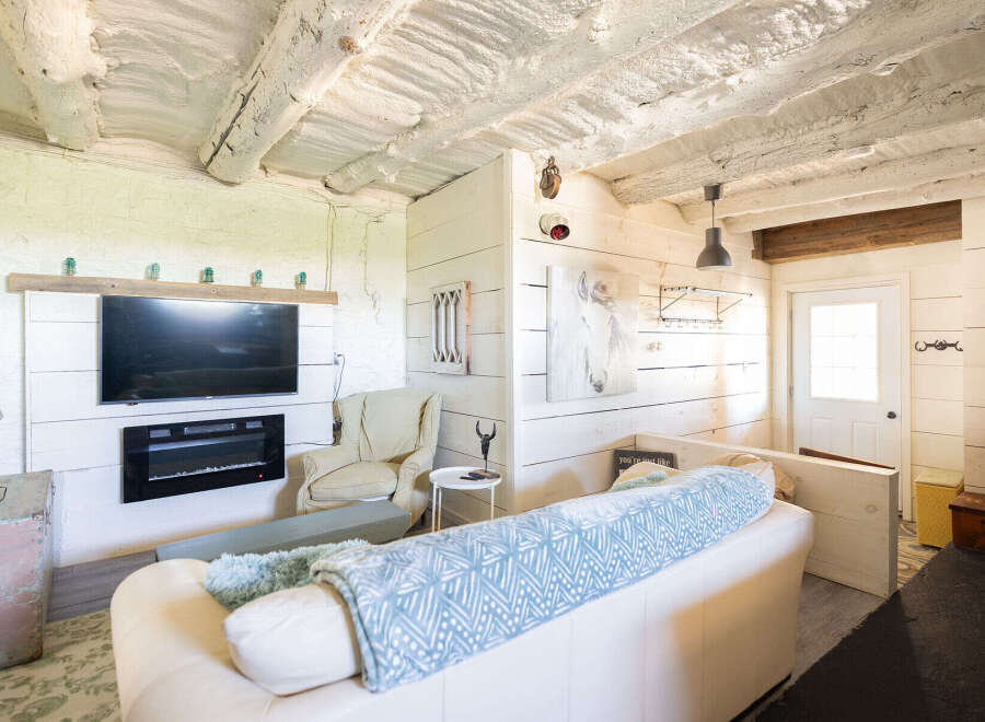 Experience rustic charm in this cozy living space featuring a modern electric fireplace and a large flat-screen TV mounted above.