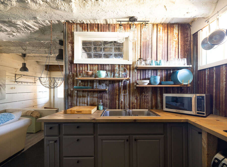 Discover this charming kitchen featuring rustic corrugated metal walls and a butcher block countertop.