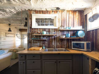 Discover this charming kitchen featuring rustic corrugated metal walls and a butcher block countertop.