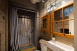 This rustic bathroom features a unique corrugated metal shower with a grey textured curtain, adding a touch of industrial charm.
