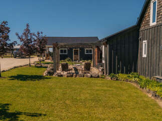 Experience rustic charm and modern comfort in this picturesque property featuring a dark wood exterior and a welcoming patio area.