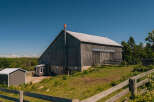 Discover this charming rural property featuring a classic wooden barn with a metal roof, perfect for agricultural use or conversion into a unique event space.