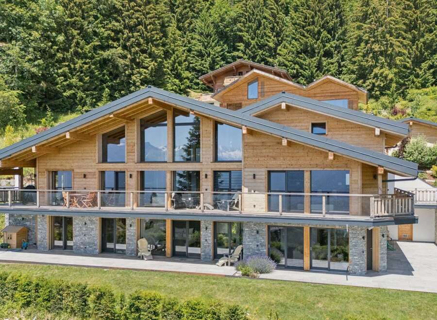 Experience luxury mountain living in this stunning wooden chalet, featuring expansive floor-to-ceiling windows that showcase breathtaking alpine views.