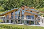 Experience luxury mountain living in this stunning wooden chalet, featuring expansive floor-to-ceiling windows that showcase breathtaking alpine views.
