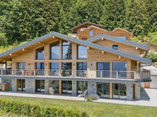 Experience luxury mountain living in this stunning wooden chalet, featuring expansive floor-to-ceiling windows that showcase breathtaking alpine views.