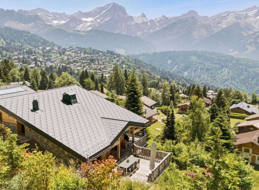 Experience breathtaking mountain views from this stunning chalet, nestled amidst lush greenery and overlooking a charming village.