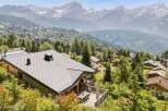 Experience breathtaking mountain views from this stunning chalet, nestled amidst lush greenery and overlooking a charming village.