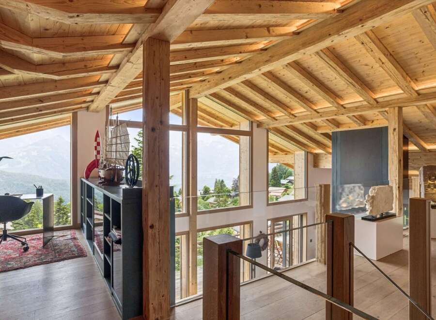 Experience breathtaking mountain views from this stunning chalet, featuring a spacious open-plan living area with exposed wooden beams and a vaulted ceiling.