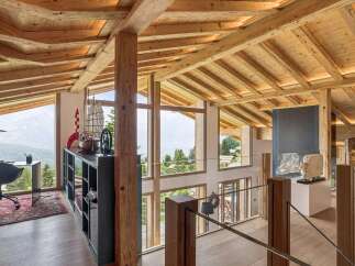 Experience breathtaking mountain views from this stunning chalet, featuring a spacious open-plan living area with exposed wooden beams and a vaulted ceiling.