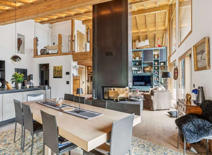 Experience luxurious alpine living in this stunning open-concept great room, featuring a soaring wood-beamed ceiling and a dramatic floor-to-ceiling fireplace.