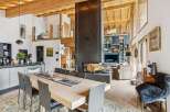 Experience luxurious alpine living in this stunning open-concept great room, featuring a soaring wood-beamed ceiling and a dramatic floor-to-ceiling fireplace.