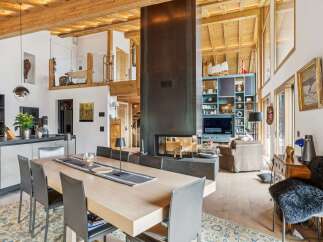 Experience luxurious alpine living in this stunning open-concept great room, featuring a soaring wood-beamed ceiling and a dramatic floor-to-ceiling fireplace.