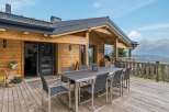 Experience breathtaking mountain views from this stunning wooden chalet, featuring a spacious outdoor dining area perfect for al fresco meals.