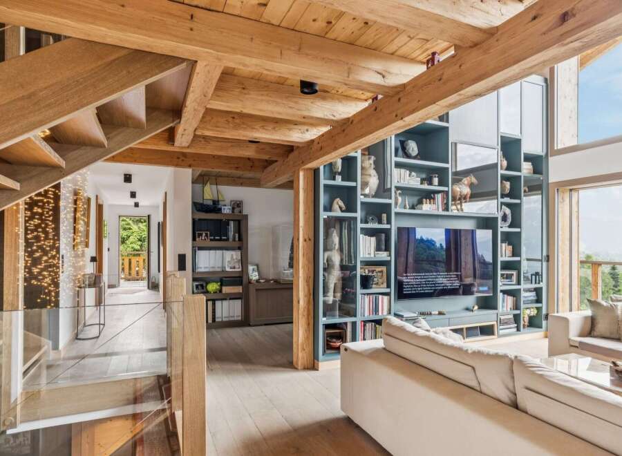Experience luxury mountain living in this stunning home featuring exposed wooden beams and a grand staircase with ambient lighting.