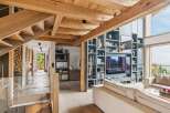 Experience luxury mountain living in this stunning home featuring exposed wooden beams and a grand staircase with ambient lighting.