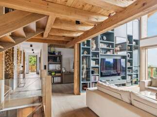 Experience luxury mountain living in this stunning home featuring exposed wooden beams and a grand staircase with ambient lighting.