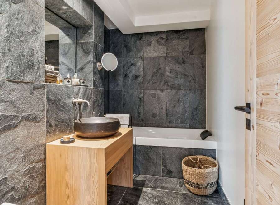 Experience modern luxury in this stunning bathroom featuring a sleek, dark stone tile design.