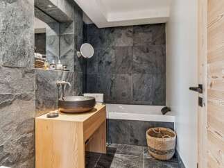 Experience modern luxury in this stunning bathroom featuring a sleek, dark stone tile design.