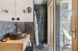 Experience luxury in this modern bathroom featuring a striking stone vessel sink atop a warm wooden vanity.